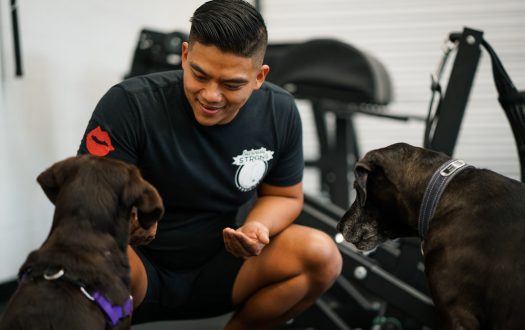 Seriously Strong Training coach greeting two dogs in the gym